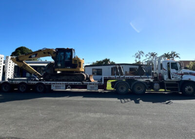Low loader transporting demolition excavator to project site